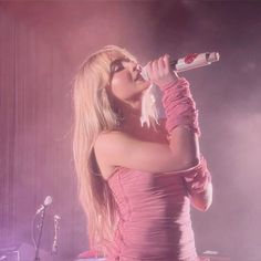 a woman in a pink dress singing into a microphone