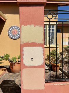 the outside of a house with some paint on it and plants in pots next to it