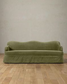 a green couch sitting on top of a hard wood floor next to a white wall