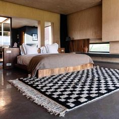 a bedroom with a large bed and black and white rug on the floor next to it