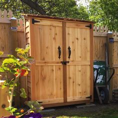 a wooden storage shed with two doors on each side and a wheelbarrow behind it