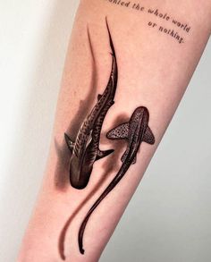 an arm tattoo with two fish on it, one is black and the other is white