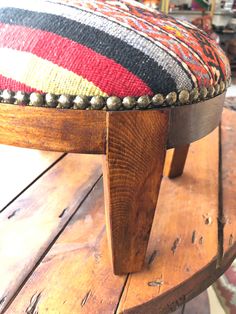 a wooden bench with a multicolored cushion sitting on it's back end