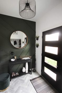 a room with a black door, mirror and rug on the floor in front of it