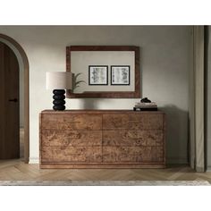 a large wooden dresser sitting next to a lamp on top of a hard wood floor