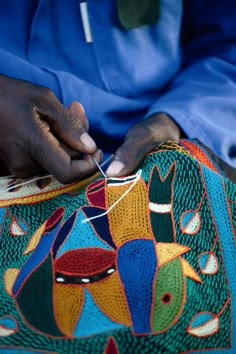 a person is stitching something on a colorful cloth