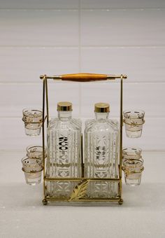 an old fashioned set of liquor bottles and shot glasses on a tray with gold rims