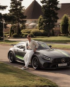 a man sitting on the hood of a sports car