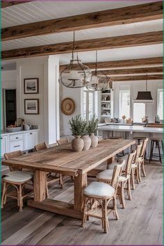 a large wooden table surrounded by chairs in a room with white walls and wood beams