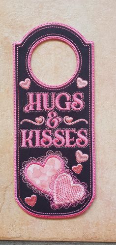 a black and pink bib with hearts on it that says hugs and kissess