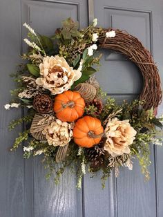 a wreath with flowers and pumpkins on the front door