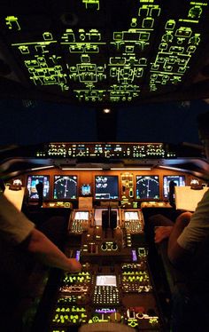 two pilots are sitting in the cockpit of an airplane with green lights on it's windows