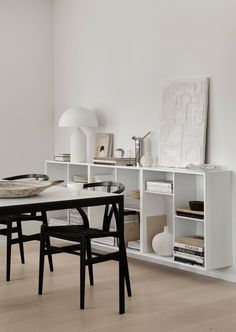 a dining room table and chairs in front of a white wall