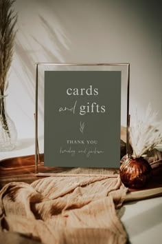 a sign that says cards and gifts on it next to some dried grass in a glass vase