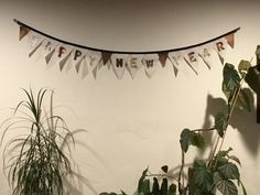 there is a banner that says happy new year hanging on the wall next to some plants