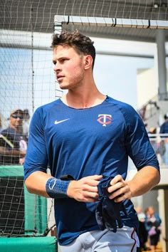 a baseball player is holding his glove while standing in front of the dugout