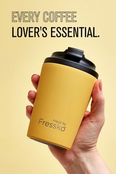 a hand holding a yellow coffee cup with the words every coffee lover's essential