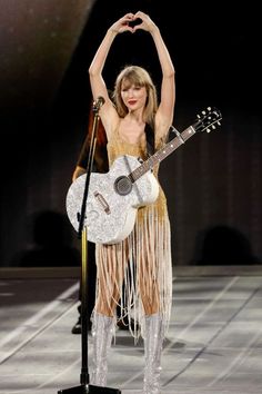 taylor swift performing on stage with her guitar