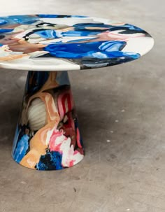 a multicolored table sitting on top of a cement floor