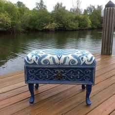 a blue bench sitting on top of a wooden deck next to water and trees in the background