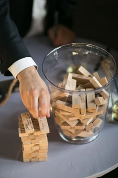 a person is playing with wooden blocks on a white tablecloth and glass vase filled with water