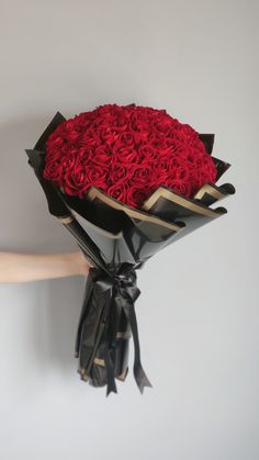 a bouquet of red roses is held up against the wall by someone's hand