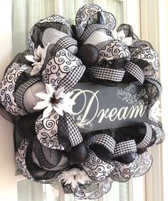 a black and white wreath hanging on the side of a door with an inscription dream