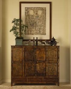 a wooden cabinet with sculptures on top and a painting above it