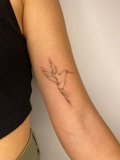 a woman's arm with a small bird tattoo on the left side of her arm