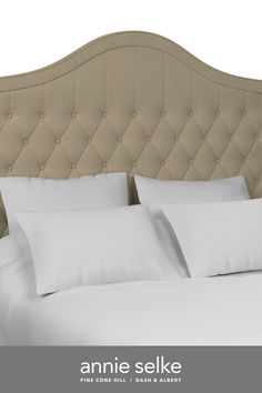 an upholstered headboard with white pillows and linens on the bottom bed