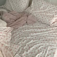 an unmade bed with pink and white sheets