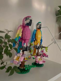 two lego figurines standing next to each other on top of a shelf in front of a potted plant