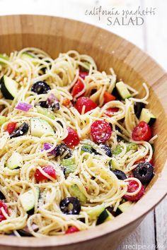 a close up view of a pasta salad with olives, tomatoes and cucumbers