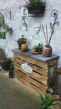 an outdoor bar made out of pallet wood with plants on top and potted plants on the side