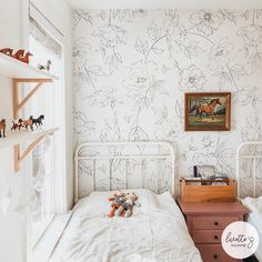 two twin beds in a small room with white walls and floral wallpaper on the walls