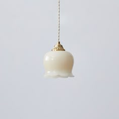 a white light hanging from a gold chain on a gray background with no one in it