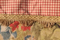 close up view of the fabric and fringes on a floral patterned chair cushion, with red and white checkerboard pattern