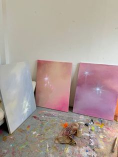 three paintings are sitting on the floor in an art studio