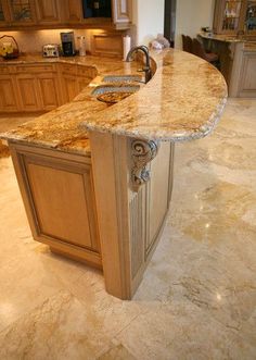 a large kitchen with marble counter tops and wooden cabinetry, along with an island in the middle