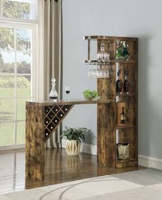 a wooden table with wine glasses and bottles on it in front of a large window