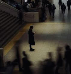 a man standing in the middle of a subway station while looking at his cell phone