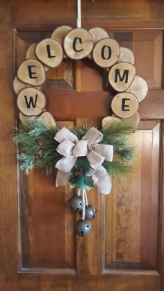 a wreath with the word welcome hanging from it's side on a wooden door