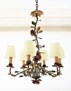 a chandelier with four lamps hanging from it's sides and flowers on the bottom