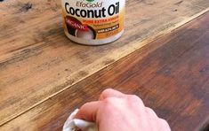 a person is wiping down the wood on top of a table with a can of coconut oil