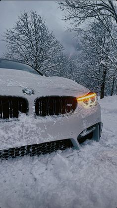 the front end of a white car covered in snow