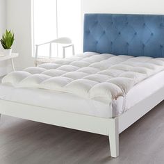 a white bed with a blue headboard and foot board next to a window in a room