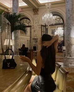 a woman sitting at a table in a fancy hotel lobby looking at her cell phone