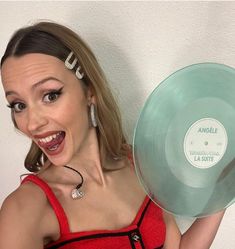 a woman holding up a green disc with the word angelie on it's side