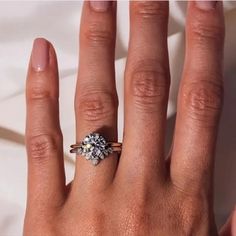 a woman's hand with an engagement ring on top of her finger and the other half of her left hand