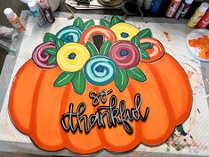 a painting of a pumpkin with the words so thank written on it and flowers in the center